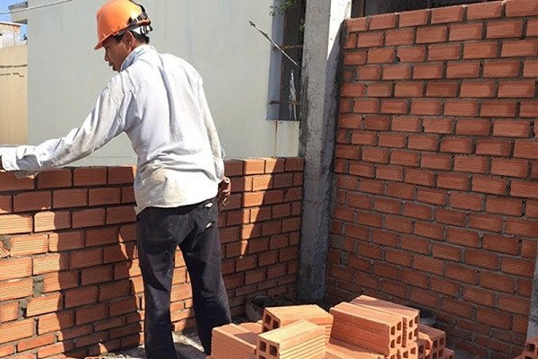 Gia chủ đang kiểm tra bản vẽ thiết kế để tuân thủ luật xây nhà sát vách.