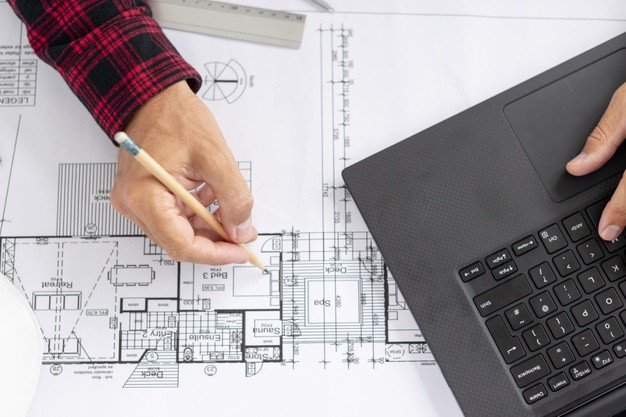 Kiến trúc sư đang làm việc trên bản vẽ thiết kế, thể hiện quy trình lên kế hoạch xây nhà trọn gói.